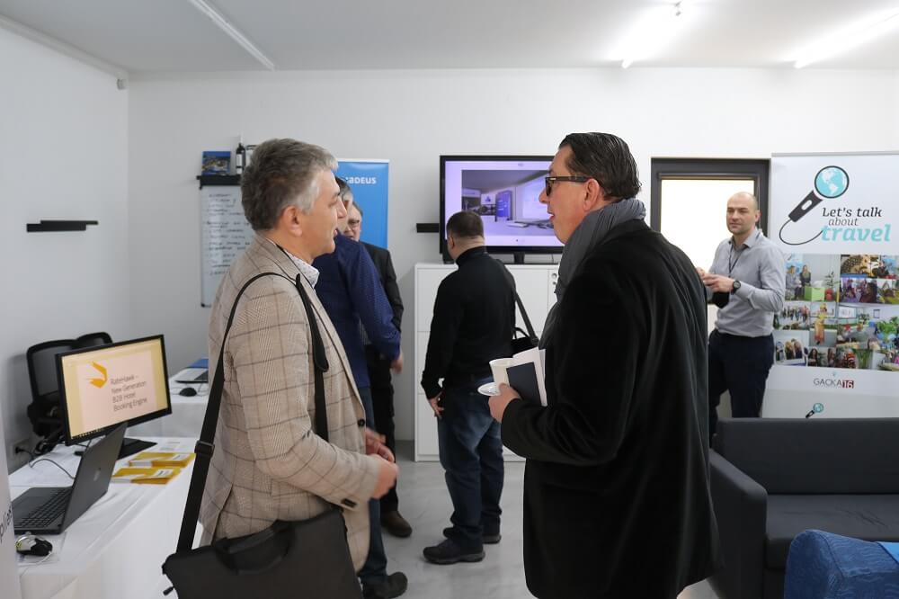 Posjetitelji konferencije razgovaraju uz izložbene panoe i zaslon s prezentacijom